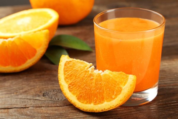 Orange Juice: Energize and Supercharge Your Health A glass of freshly squeezed orange juice with whole oranges on a wooden table.
